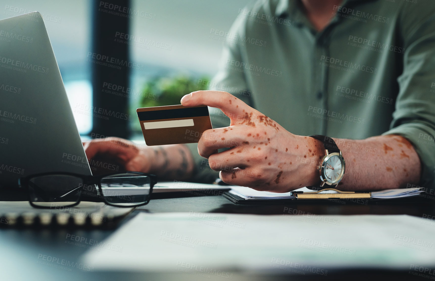 Buy stock photo Shot of an unrecognizable businessman holding a credit card while using a laptop in an office at work