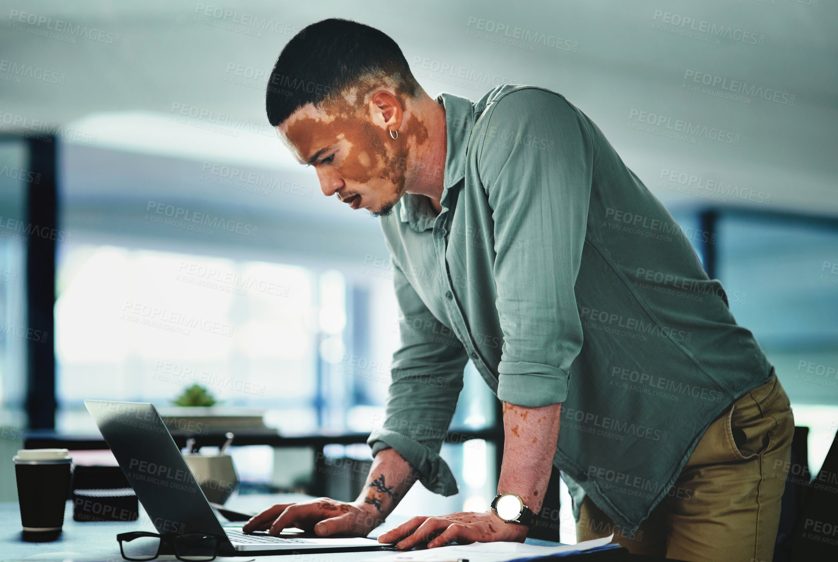 Buy stock photo Shot of a young businessman using a laptop in an office at work