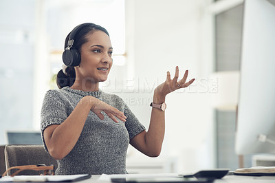 Buy stock photo Shot of a young businesswoman wearing headphones during a video call on a computer in an office