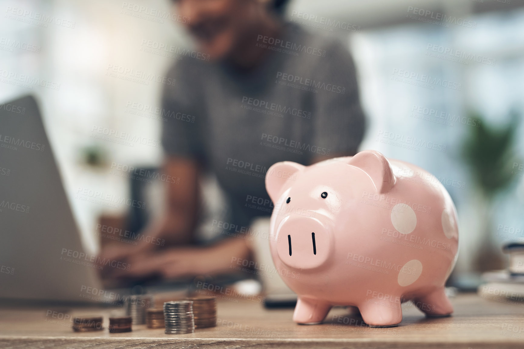 Buy stock photo Closeup shot of coins and a piggybank on a table with an unrecognisable businesswoman working in the background