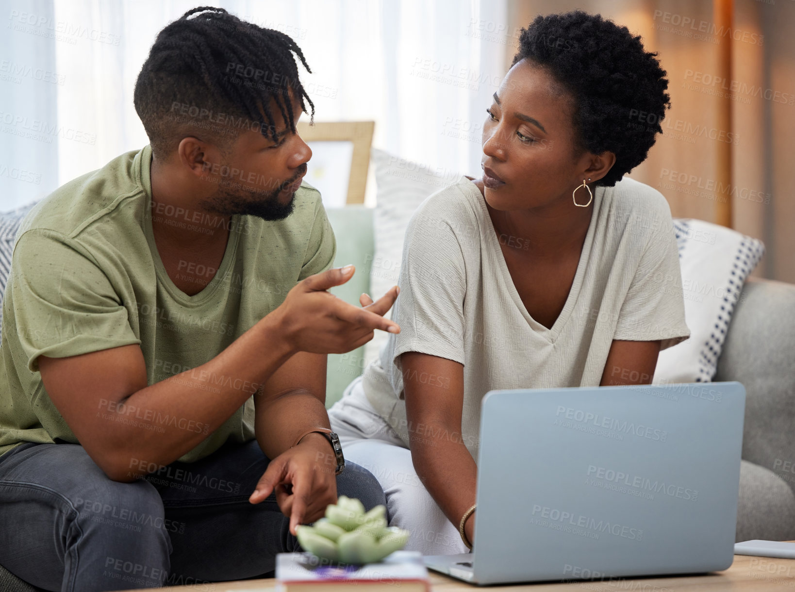 Buy stock photo Shot of a young couple using a laptop while sitting on the couch at home