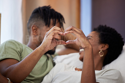 Buy stock photo Shot of two young people making a heart gesture with their hands at home