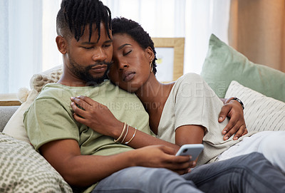 Buy stock photo Shot of a young man using a smartphone while embracing his partner at home