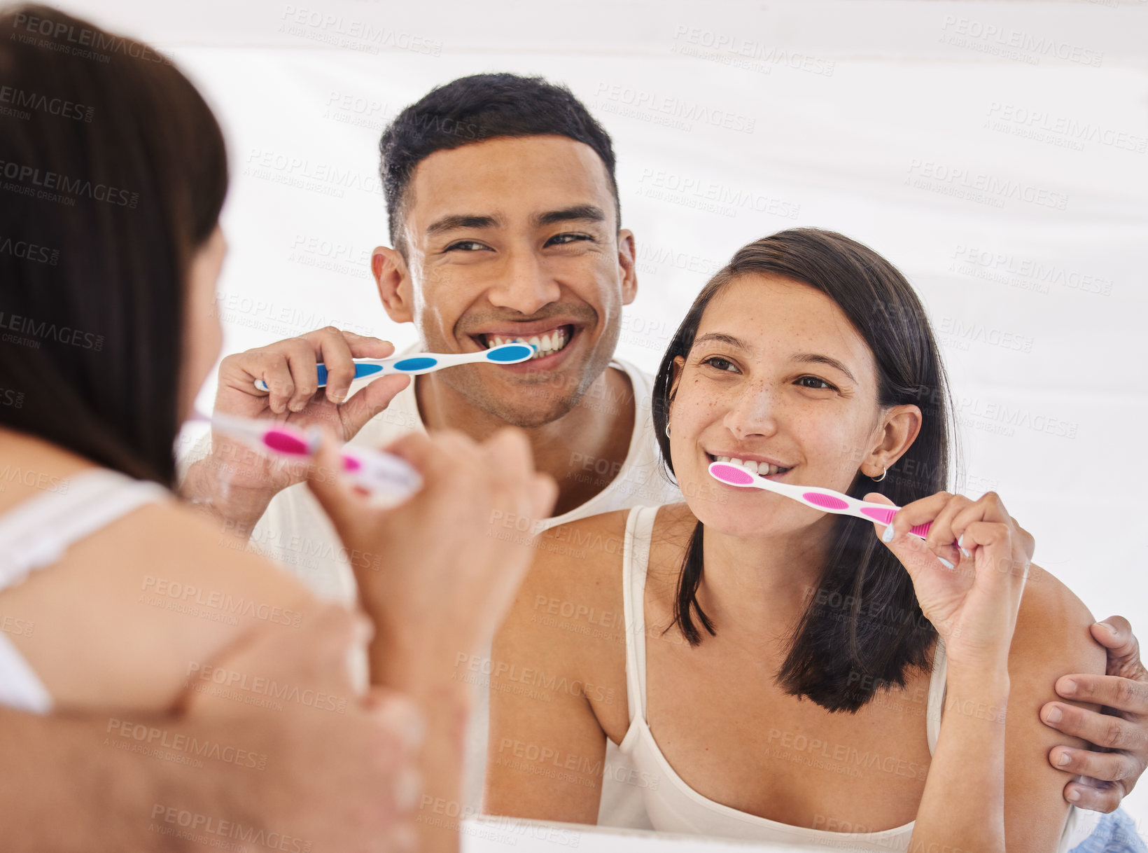 Buy stock photo Shot of a happy young couple standing together in their bathroom and brushing their teeth