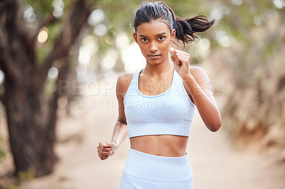 Buy stock photo Shot of a young woman jogging through a forest
