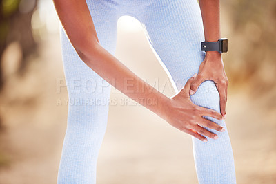 Buy stock photo Shot of a woman clutching her knee in pain during a jog