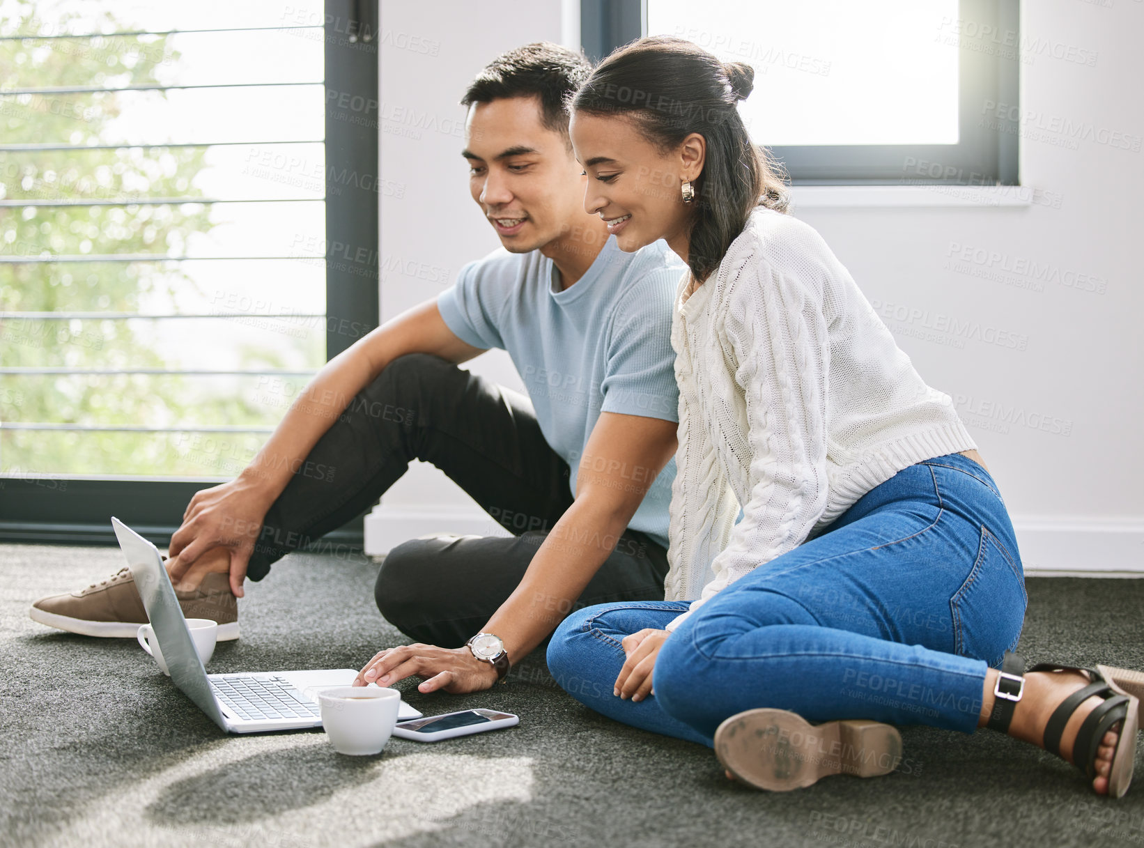 Buy stock photo Shot of a young couple sitting on the floor together in the new house and using a laptop