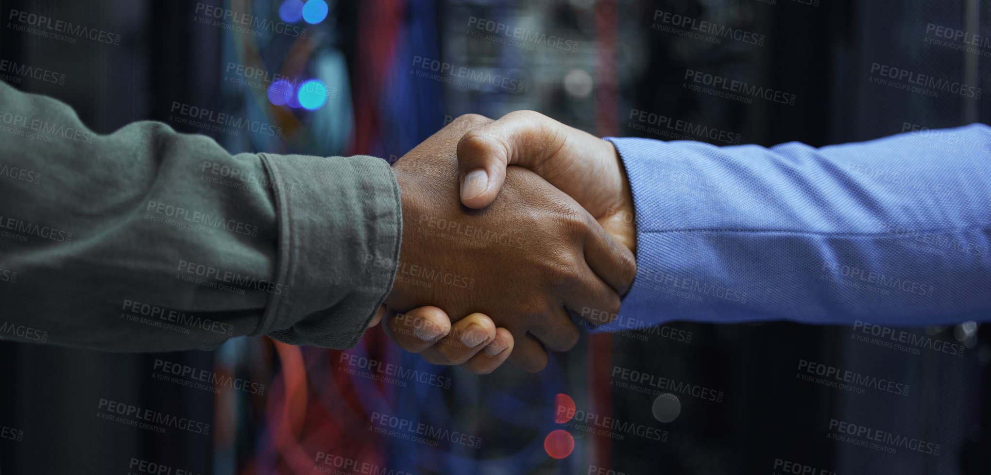 Buy stock photo Cropped shot of two unrecognizable male IT support agents shaking hands in a dark network server room