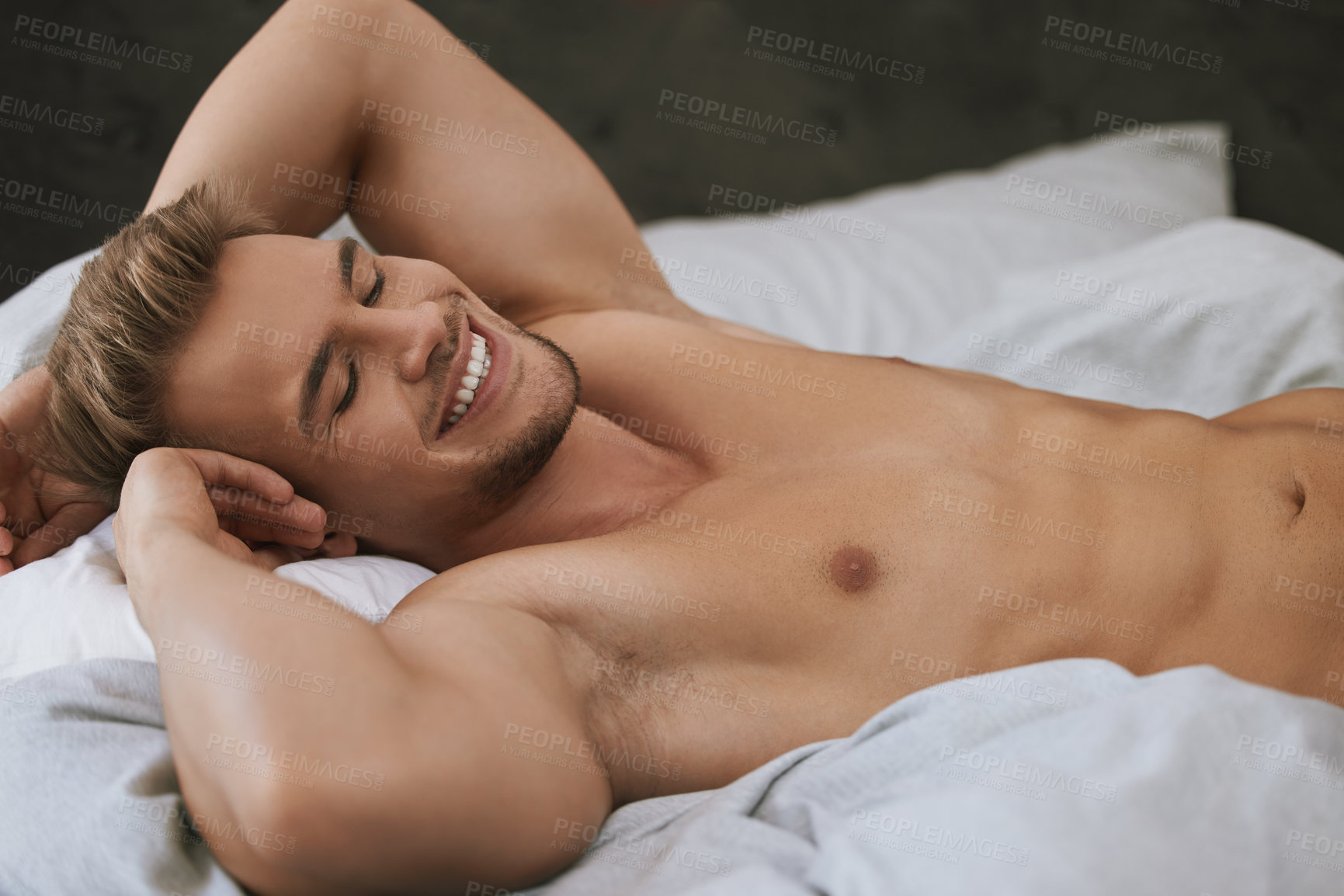 Buy stock photo Cropped shot of a handsome and muscular young man lying in his bed at home