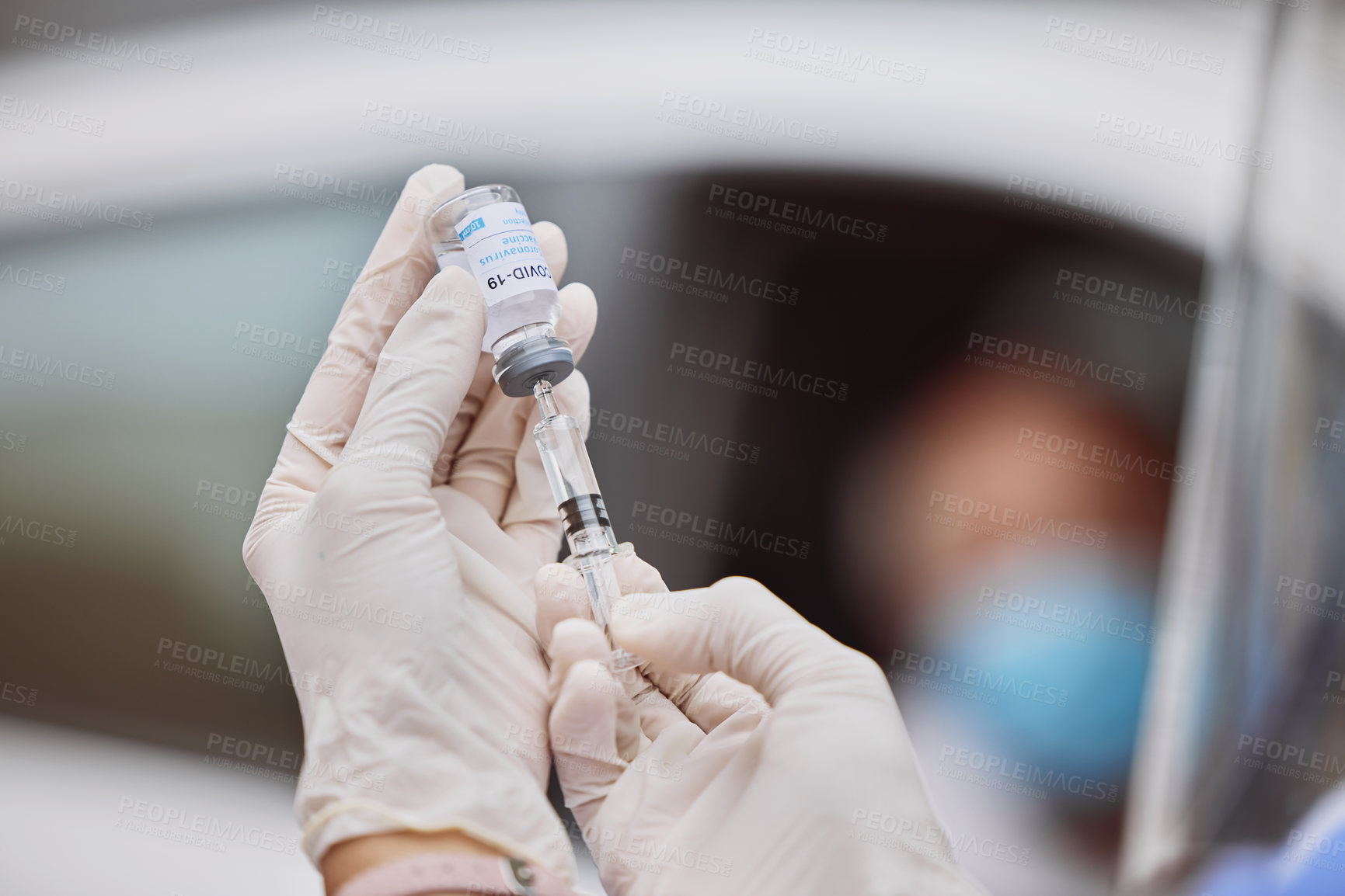 Buy stock photo Shot of an unrecognizable healthcare worker extracting liquid from a vial with a syringe at a drive through vaccination site