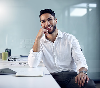Buy stock photo Shot of a young businessman sitting at his work desk