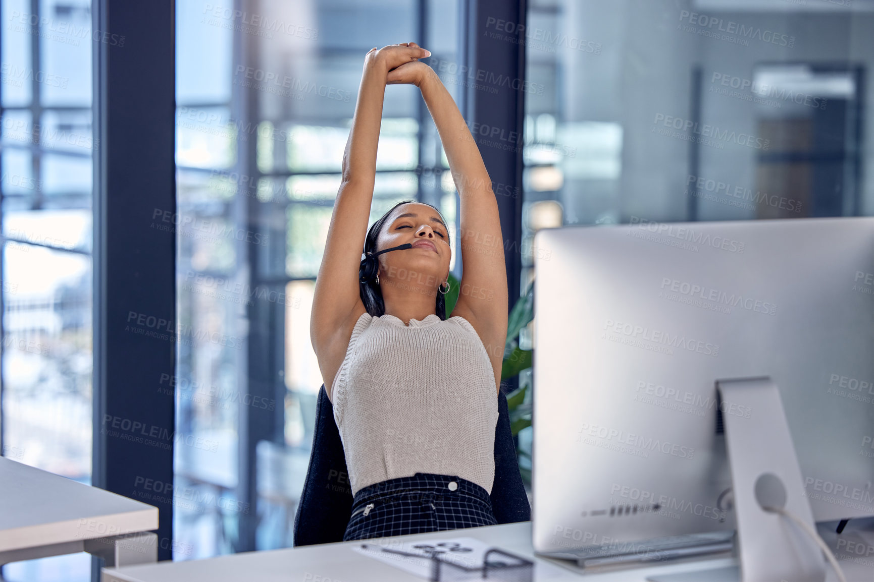 Buy stock photo Shot of a female center worker taking a break to stretch at her desk