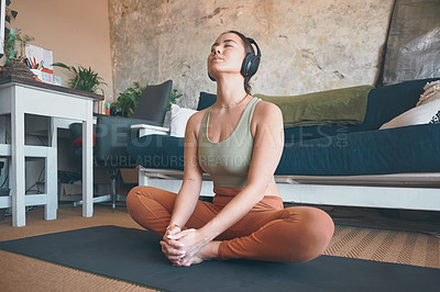 Buy stock photo Shot of a young woman wearing headphones while exercising at home