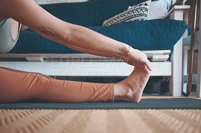 Buy stock photo Closeup shot of an unrecognisable woman touching her toes while exercising at home