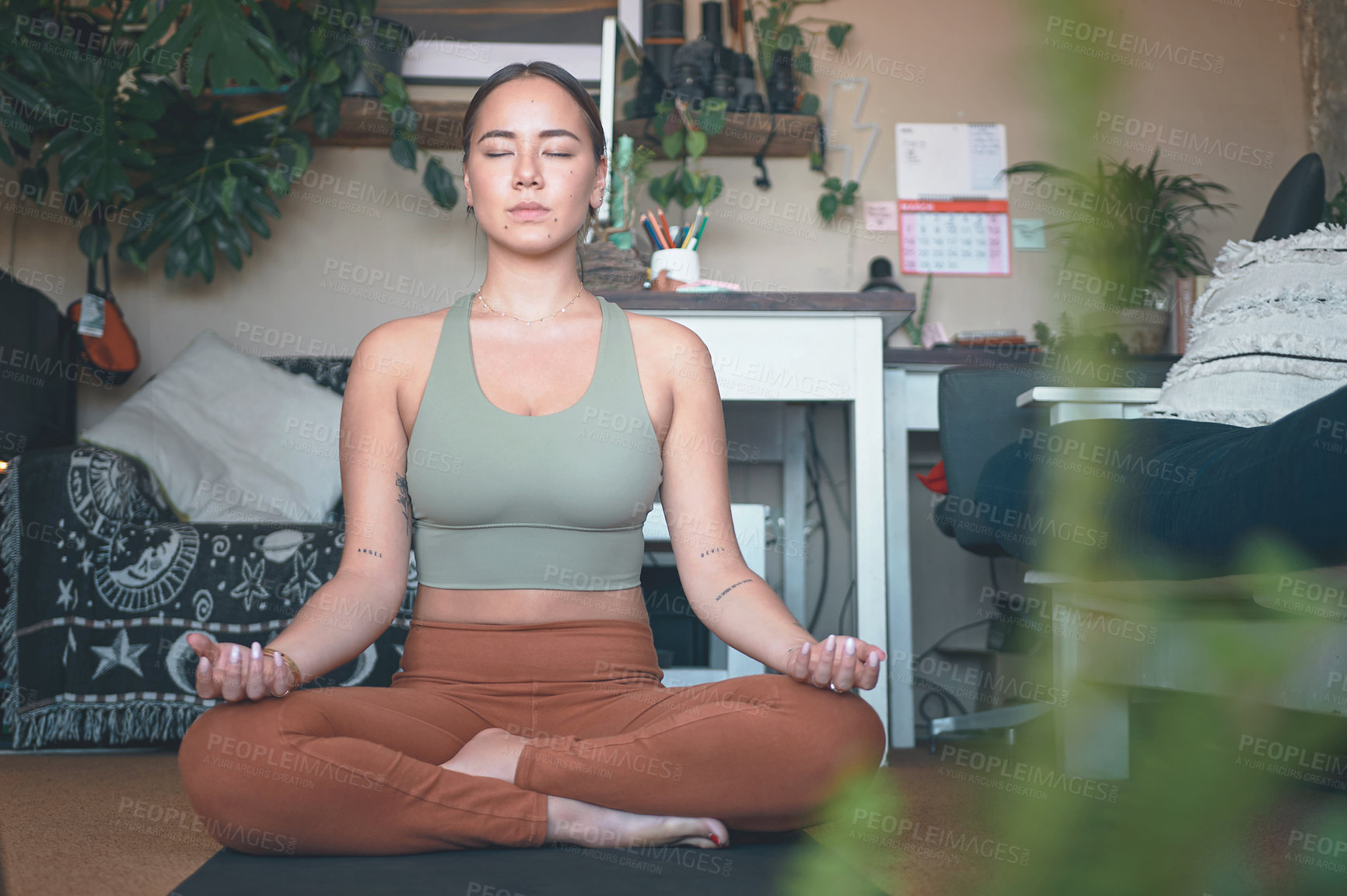 Buy stock photo Shot of a young woman meditating while practising yoga at home