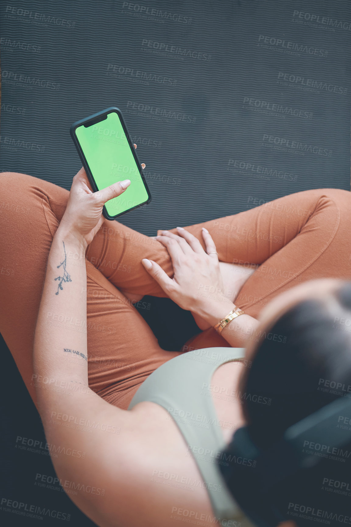 Buy stock photo High angle shot of a young woman wearing headphones and using a cellphone while exercising at home