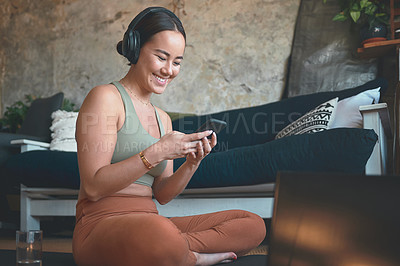 Buy stock photo Shot of a young woman using a cellphone and laptop while exercising at home