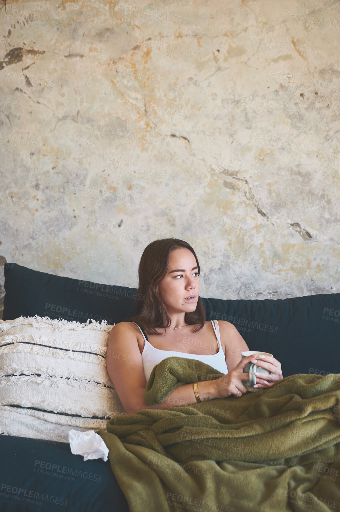 Buy stock photo Shot of a young woman having a warm drink while recovering from an illness on the sofa at home