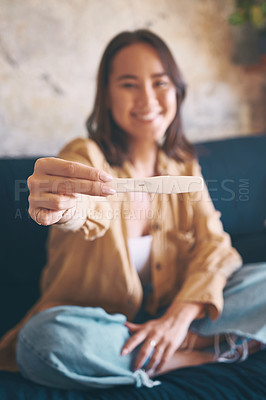 Buy stock photo Shot of a young woman taking a pregnancy test on the sofa at home