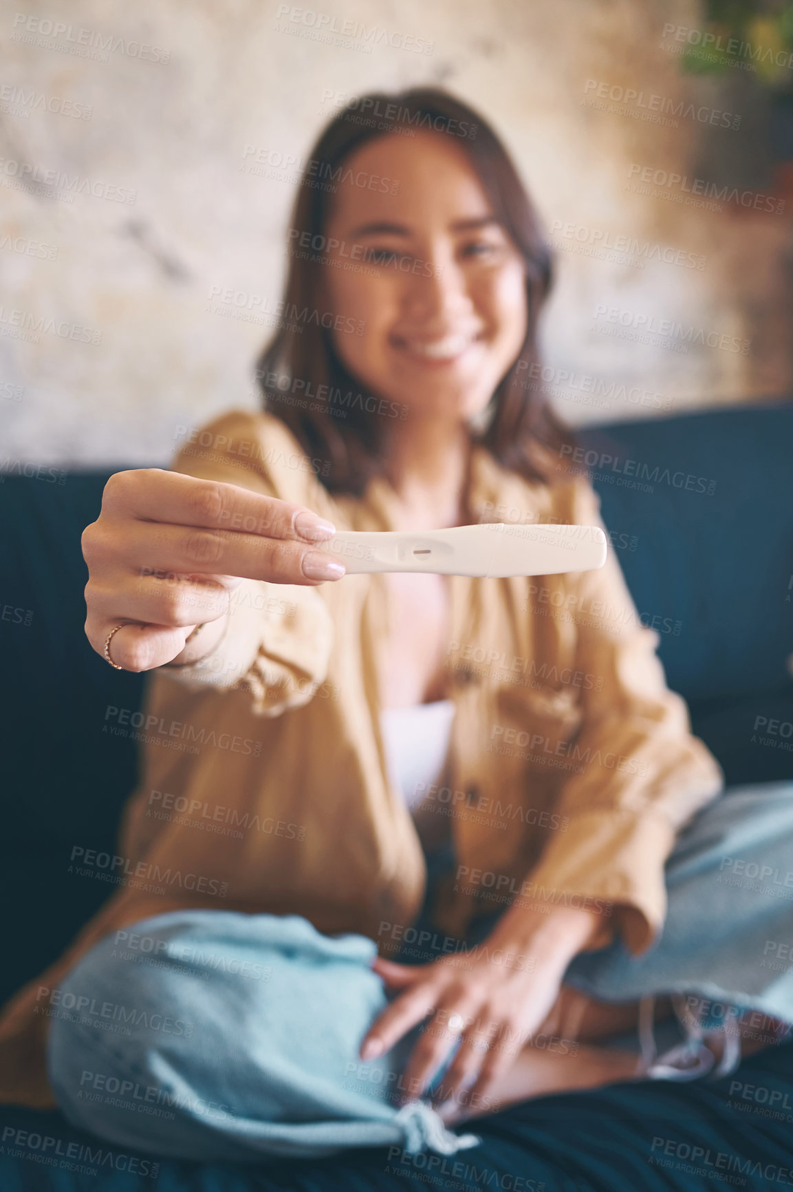 Buy stock photo Shot of a young woman taking a pregnancy test on the sofa at home