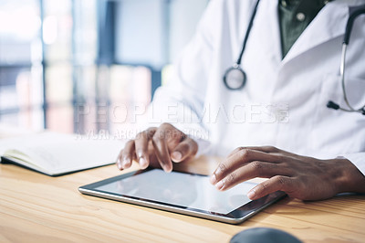 Buy stock photo Cropped shot of an unrecognizable doctor sitting alone in his office at the clinic and using his digital tablet