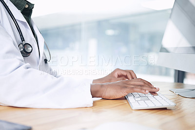 Buy stock photo Cropped shot of an unrecognizable doctor sitting alone in his office at the clinic and typing on a keyboard