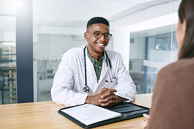 Buy stock photo Shot of a handsome young doctor sitting with his patient during a consultation in the clinic