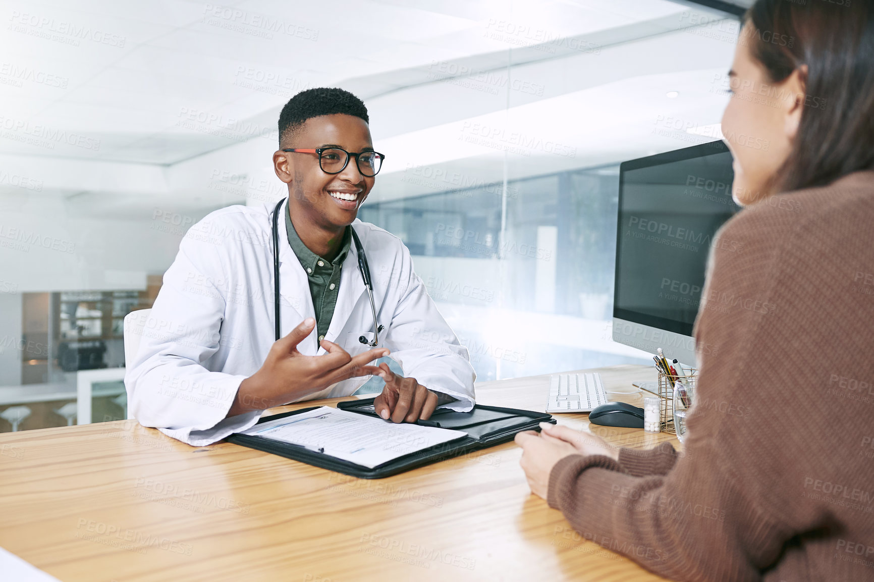 Buy stock photo Shot of a handsome doctor sitting with his patient and explaining her diagnosis during a consultation in the clinic