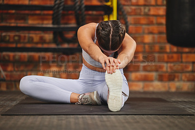 Buy stock photo Shot of a young unrecognizable woman stretching while exercising at the gym