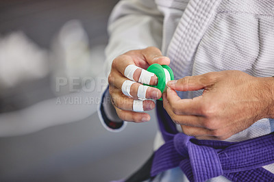 Buy stock photo Brazilian jiu jitsu, hands and person with tape in gym for training, fitness or professional fighting sport. Injury, protection and martial arts athlete with gi, safety for fingers or workout in dojo
