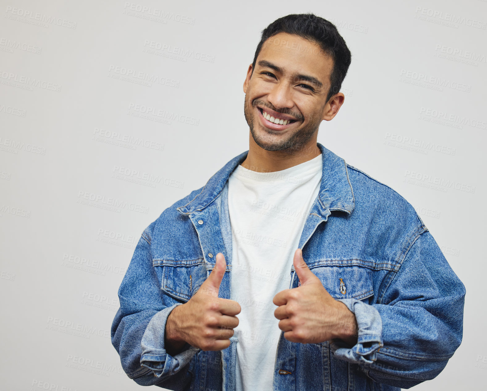 Buy stock photo Cropped portrait of a handsome young man giving thumbs up in studio against a grey background