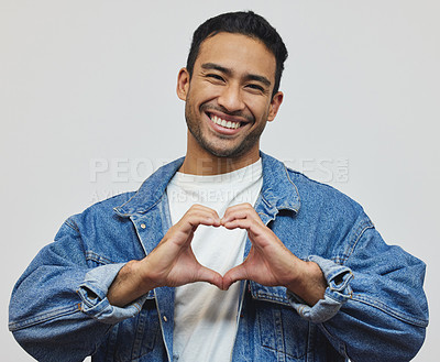 Buy stock photo Happy, man and portrait with heart sign, fashion and love hand gesture in a studio with smile. Trendy, denim and cool outfit with confidence for valentines day with jacket and grey background