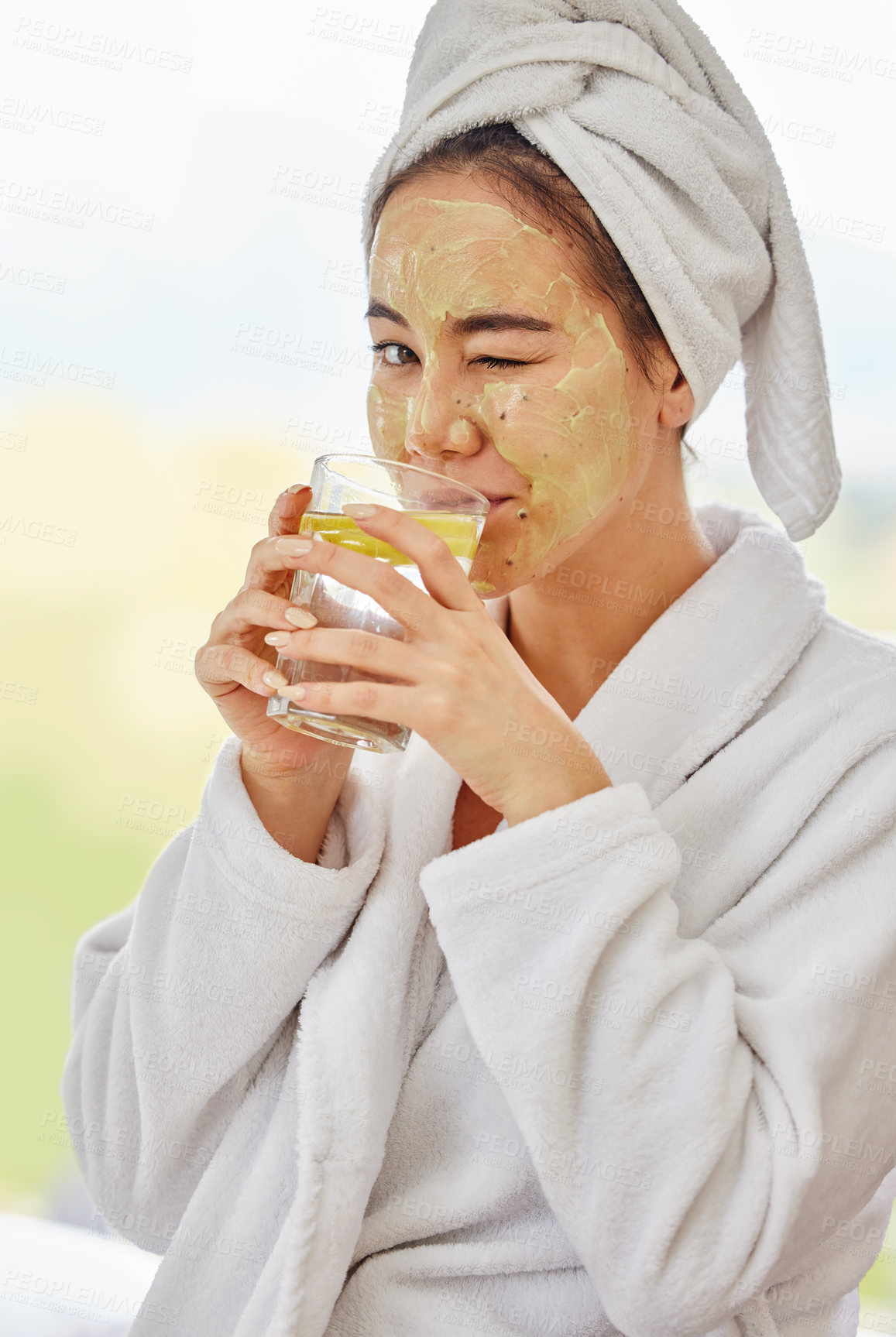 Buy stock photo Shot of a young woman drinking water while doing a facial beauty treatment at home