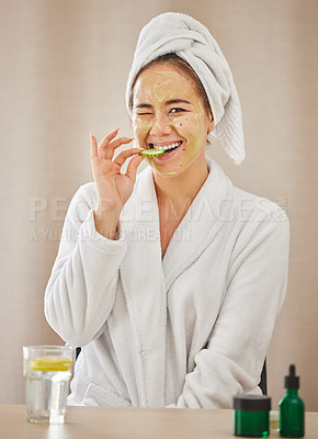 Buy stock photo Shot of a young woman eating a cucumber while doing a facial beauty treatment at home