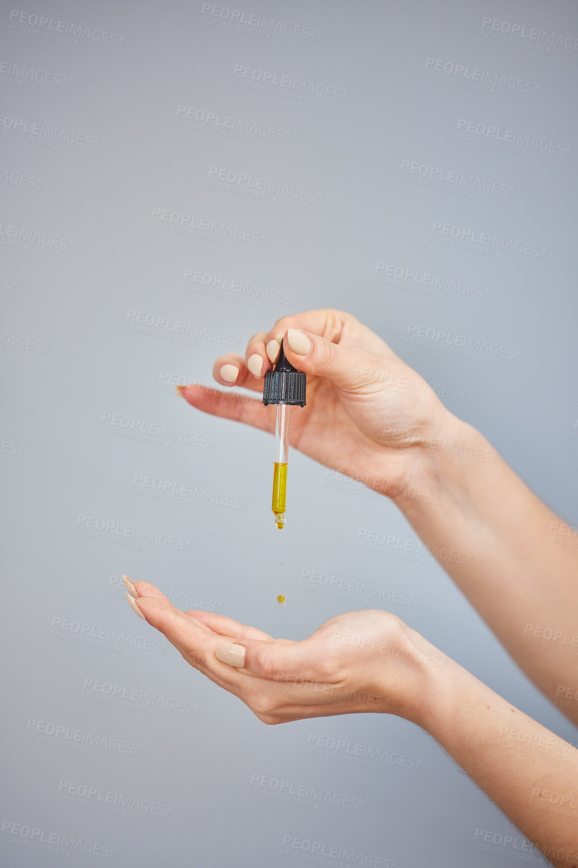 Buy stock photo Shot of a young woman taking serum from a dropper against a grey background