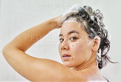 Buy stock photo Shot of a young woman washing her hair with shampoo in the shower at home