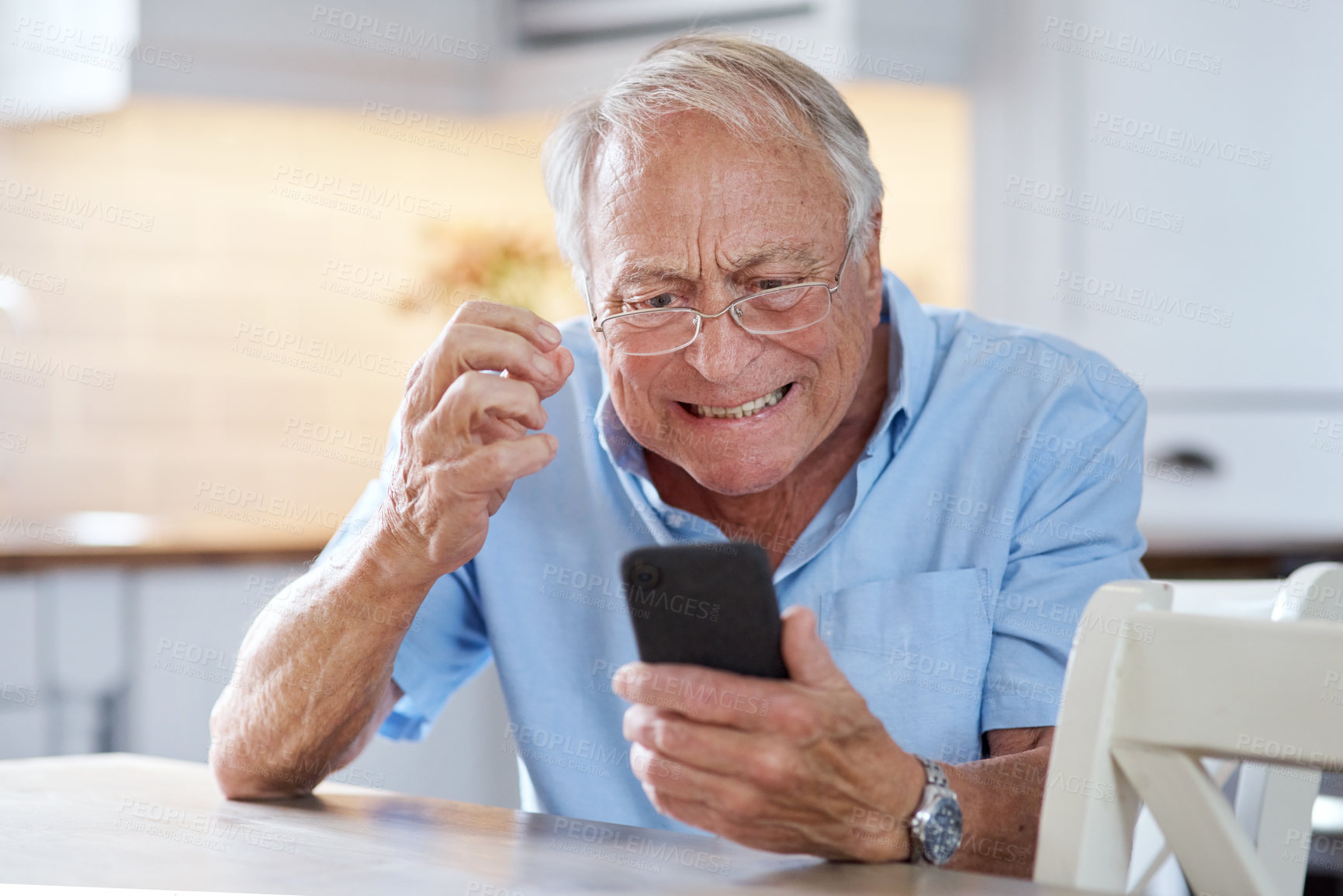 Buy stock photo Shot of an elderly man using his cellphone at the kitchen table at home