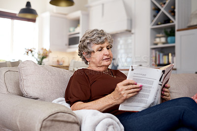 Buy stock photo Shot of an elderly woman relaxing with a book on the sofa at home