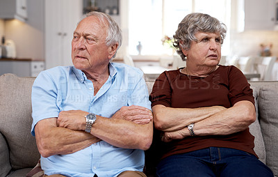 Buy stock photo Shot of an elderly couple with folding their arms and looking angry with one another on the sofa at home