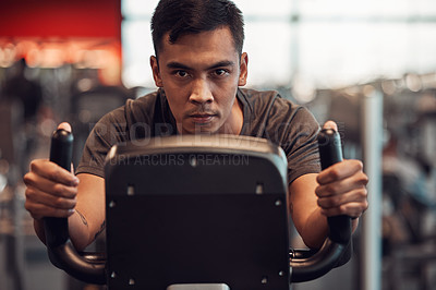 Buy stock photo Shot of a young man using an exercise bike in the gym