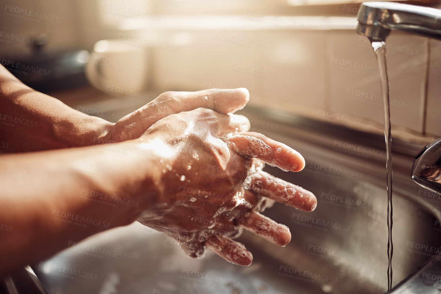 Buy stock photo Shot of an unrecognisable man washing his hands in the kitchen sink at home