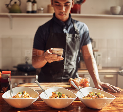 Buy stock photo Shot of a young man using a smartphone to take pictures of a healthy meal he prepared at home