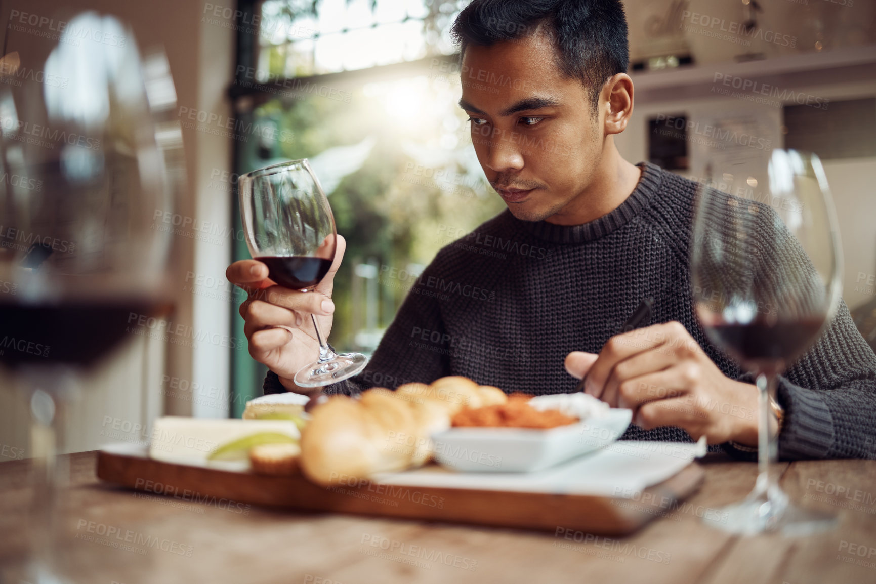 Buy stock photo Shot of a man enjoying a cheese platter and tasting different wines