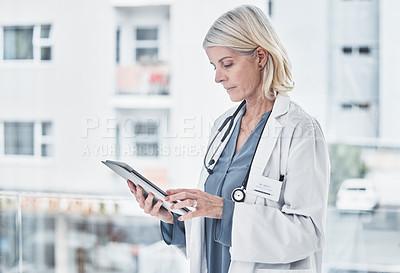 Buy stock photo Shot of a mature doctor using a digital tablet at work
