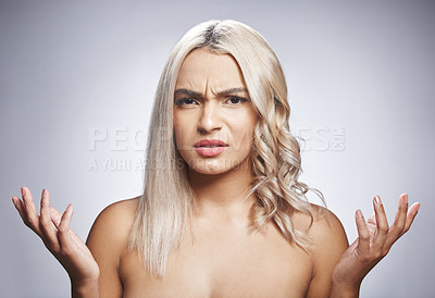 Buy stock photo Shot of an attractive young woman standing alone against a grey background in the studio and looking confused