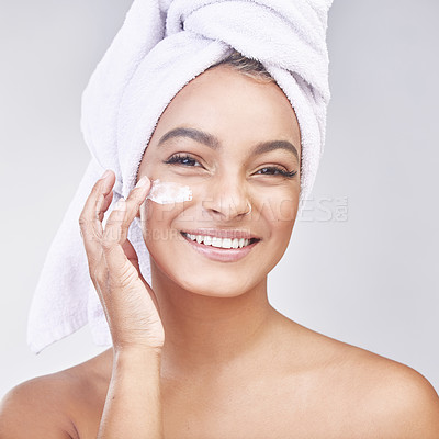 Buy stock photo Studio shot of a beautiful young woman applying moisturiser against a grey background