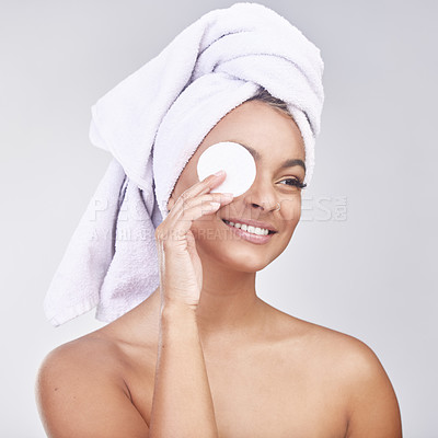Buy stock photo Studio shot of a beautiful young woman applying products to her face using a cotton disc against a grey background