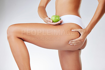 Buy stock photo Person, legs and apple or lose weight for cellulite diet in studio or fruit nutrition, self care or white background. Woman, underwear and thigh for training routine or slimming pinch or wellness