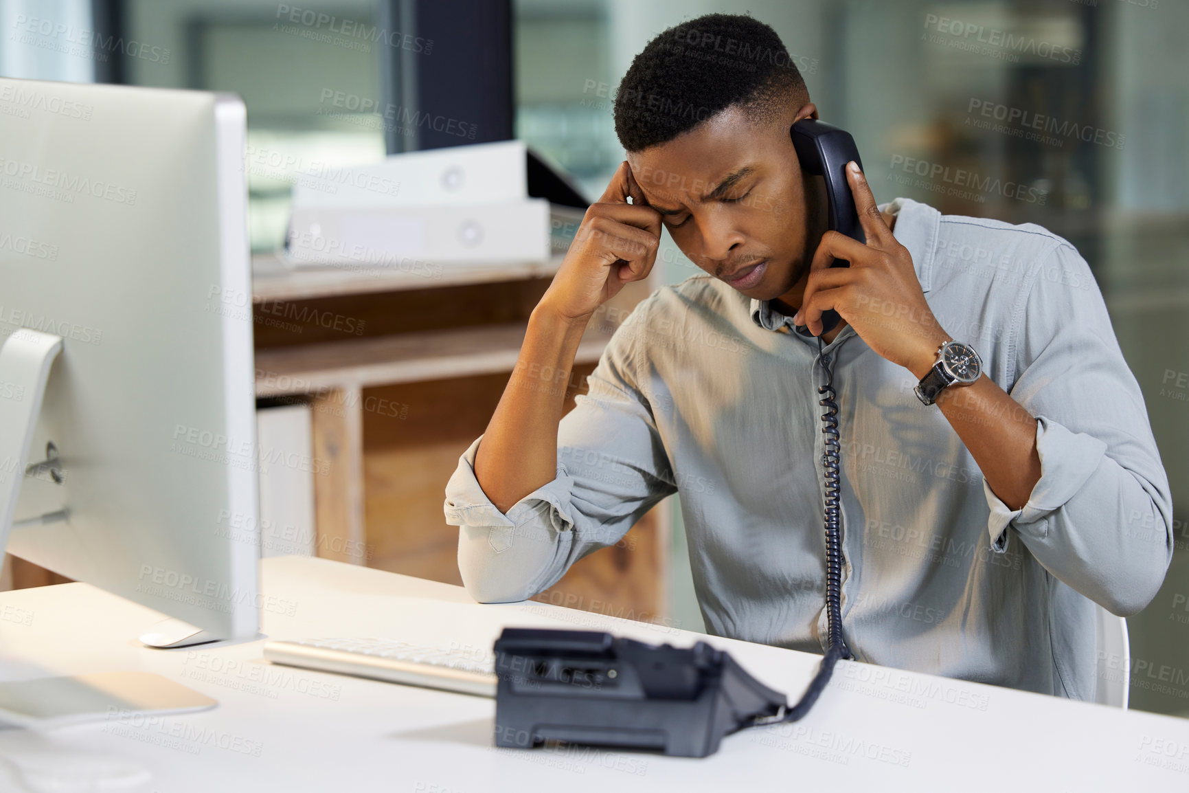 Buy stock photo Shot of a young man using a phone and looking stressed in a modern office