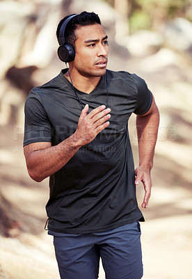 Buy stock photo Fitness, man running and with headphones outdoors in nature environment. Positive or workout, training or exercise and focus with a male athlete for health wellness or motivation in a forest.